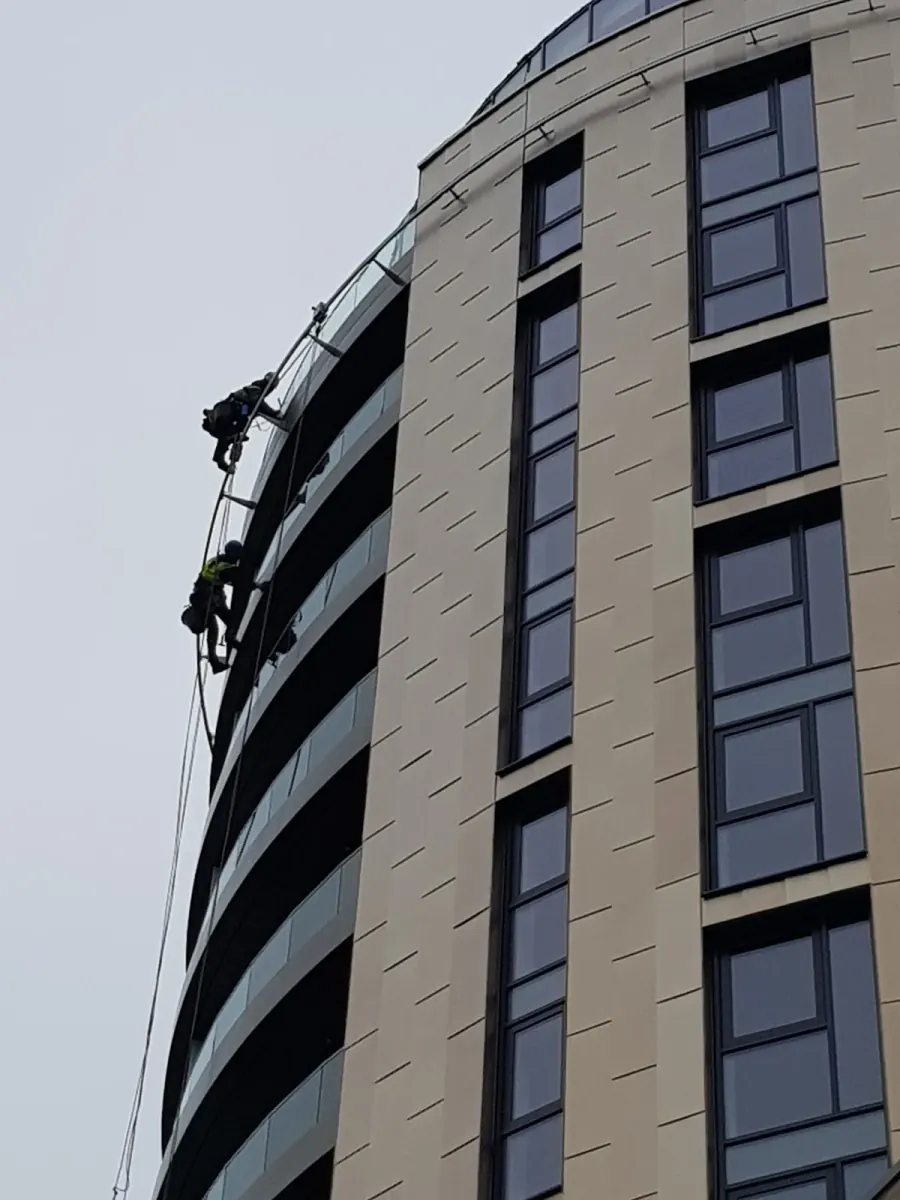 High-level window cleaning on the curved facade of a modern East London apartment block